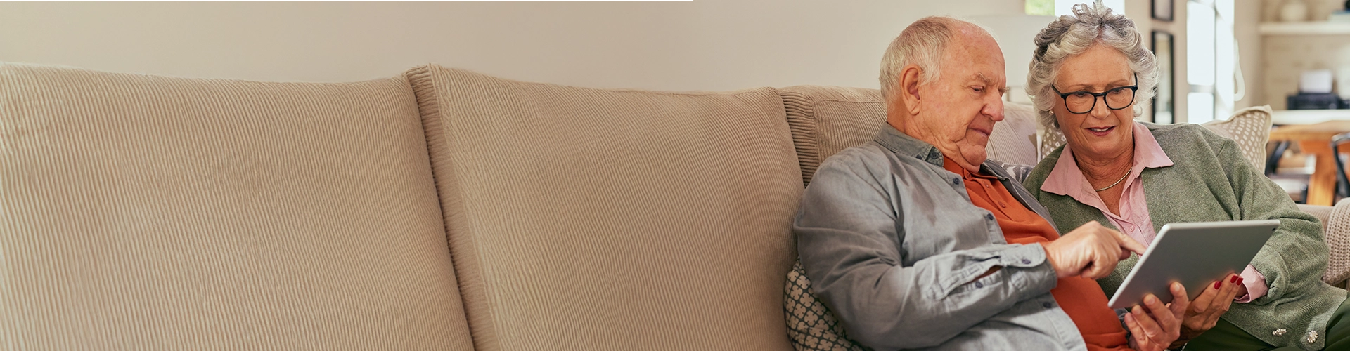 Couple sitting on couch, looking at laptop