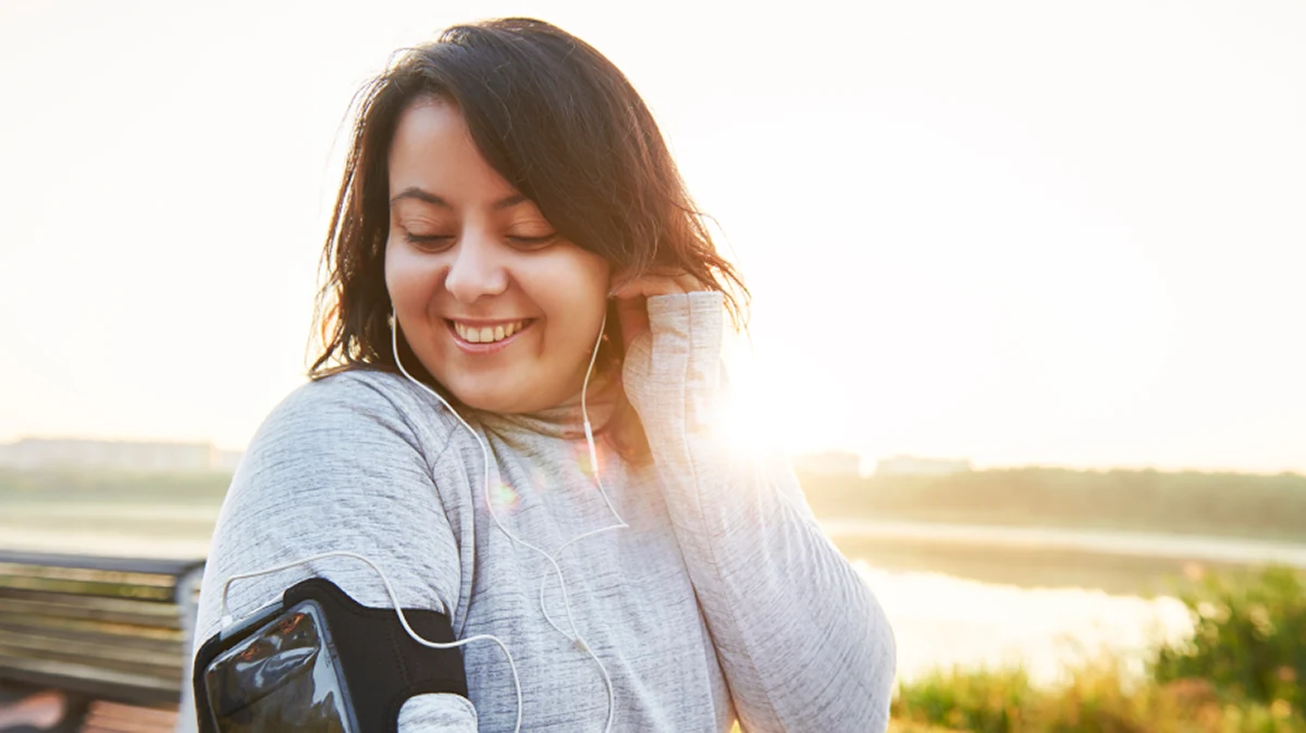Smiling woman stretching outdoors in fitness gear