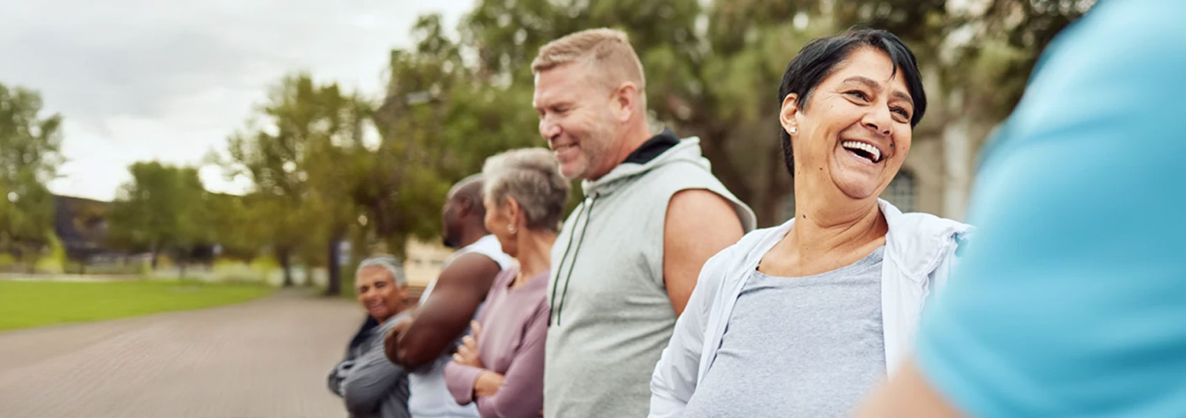 Six smiling people standing in line along a road