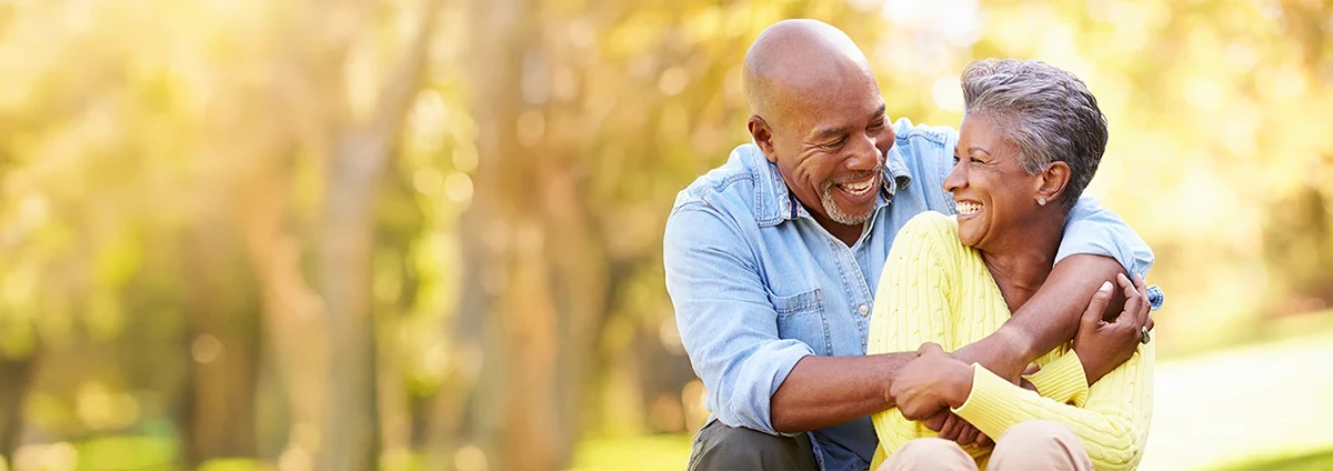 A senior woman and man smile at each other while outdoors