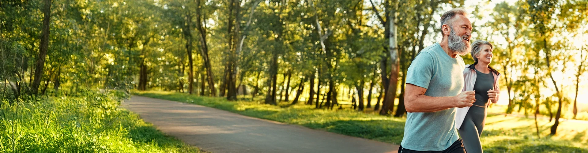 A man and woman run on a trail outside.