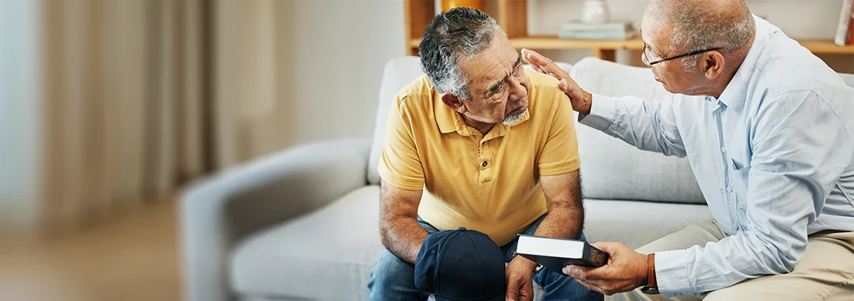 Chaplain and man sit talking on couch