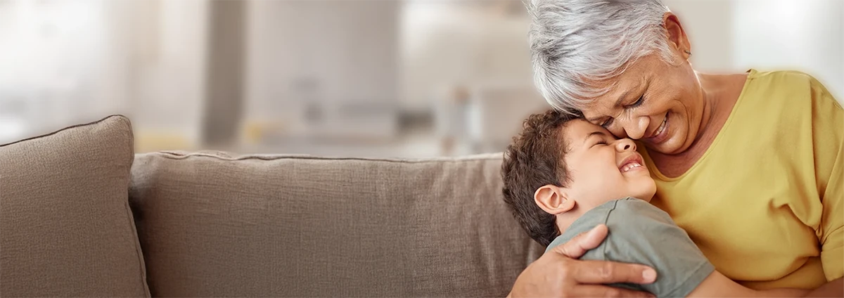 Smiling older woman hugs a young boy