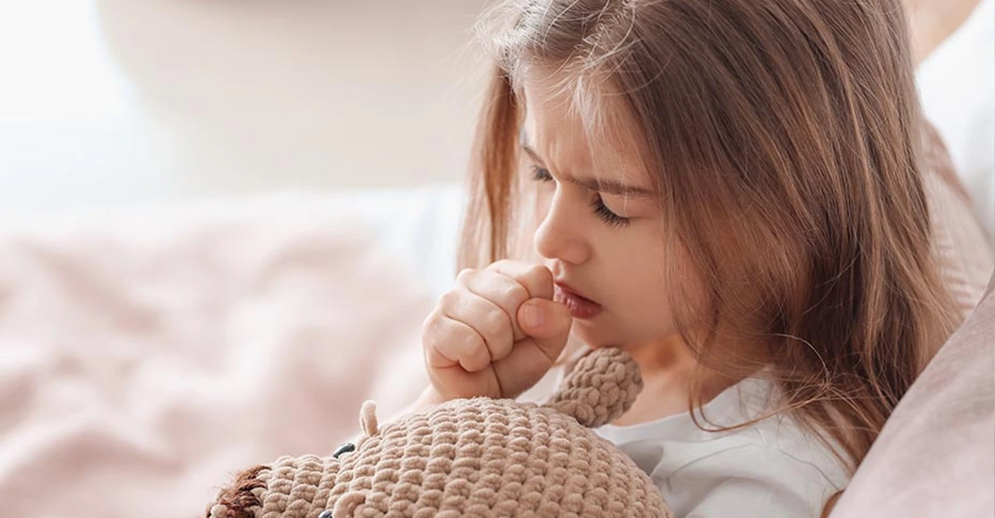 Young child with closed hand near mouth sick