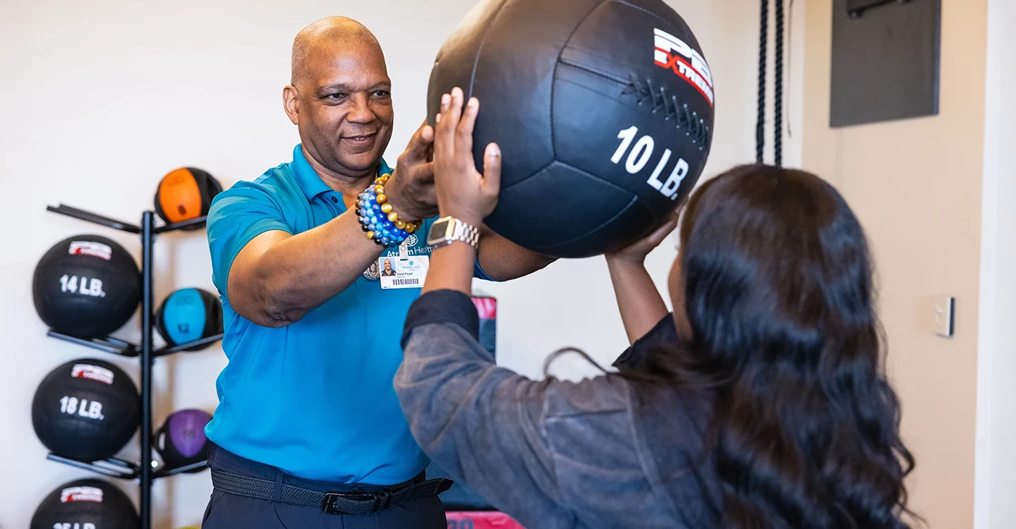 Daryl Floyd, physical therapist, works with a patient using a medicine ball
