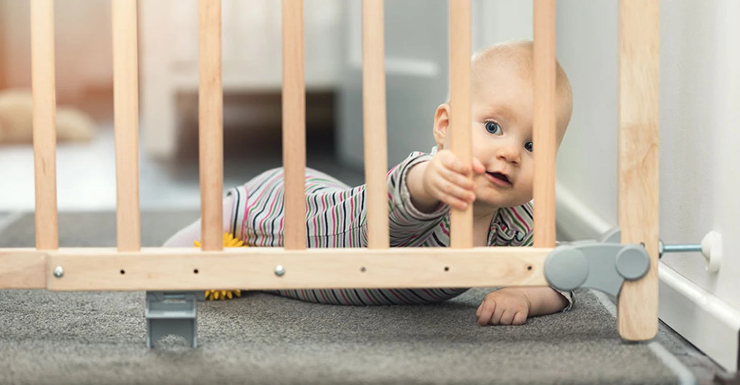 baby lying on the floor behind a baby gate
